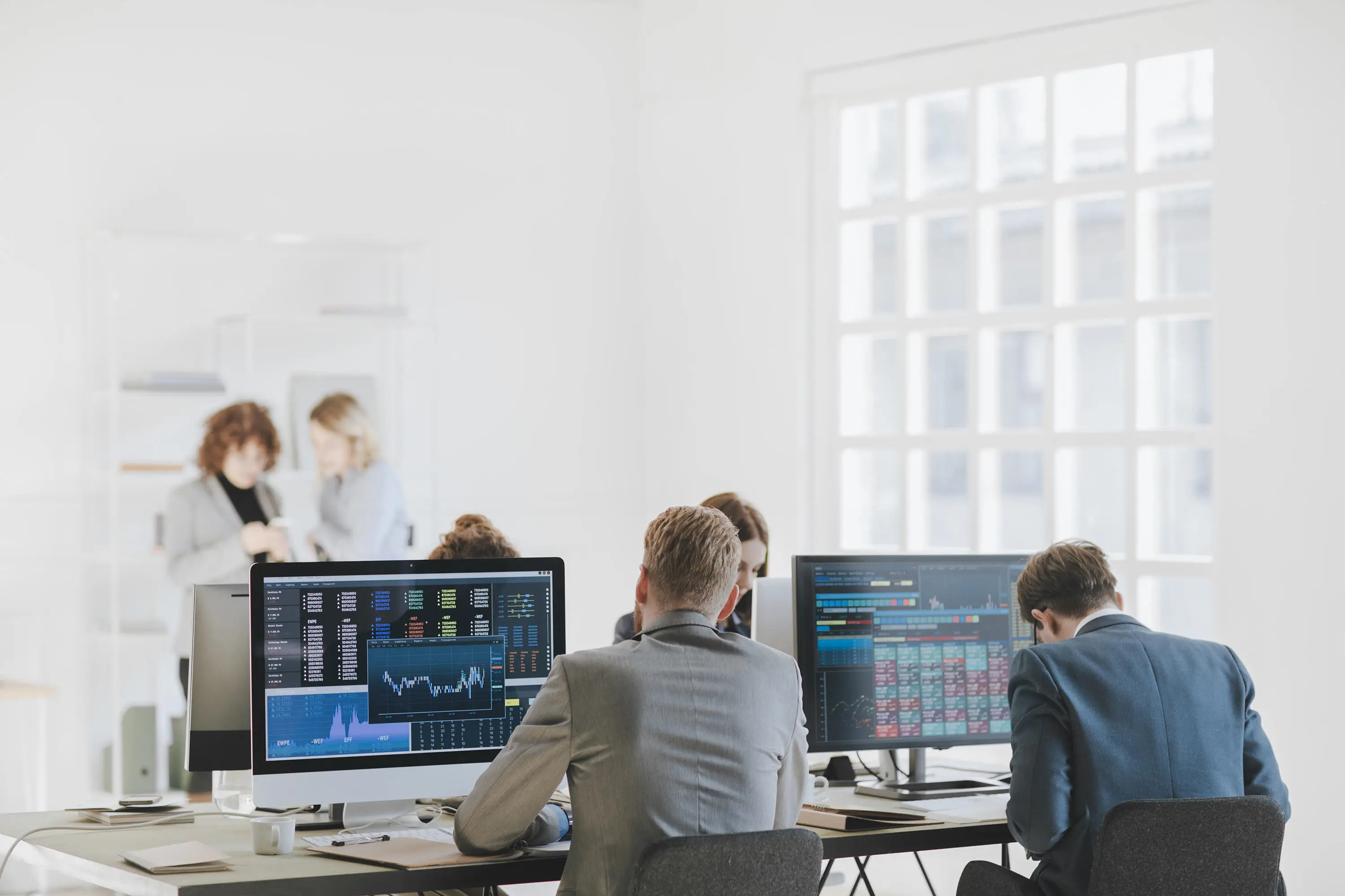 People sitting at desk in office analysing data on screens
