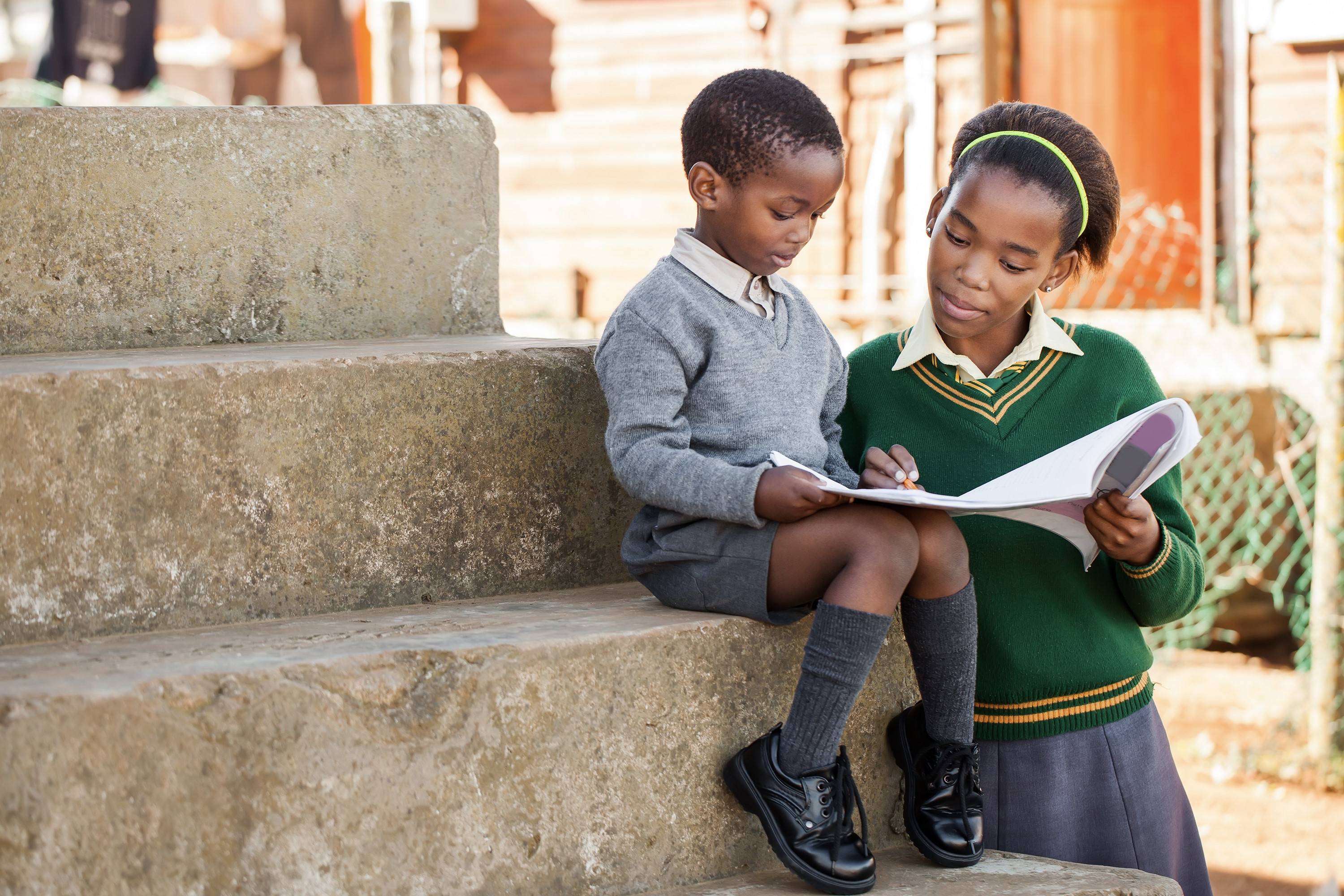 School children reading together on stone steps