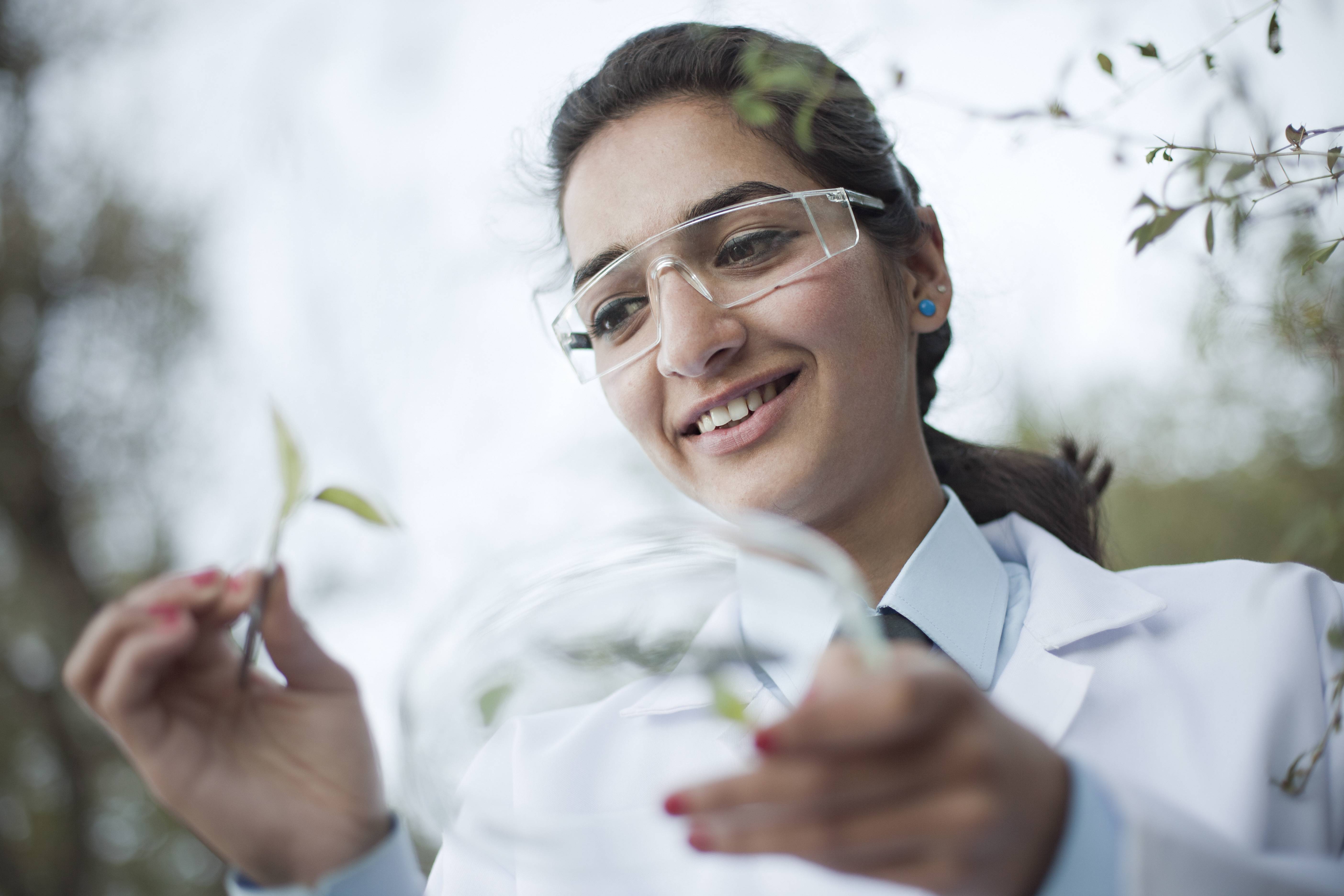 women holding plant with lab coat and glasses
