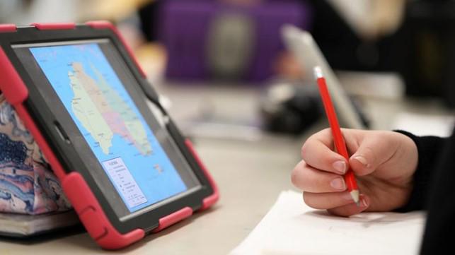 A geography student uses a tablet showing mapping