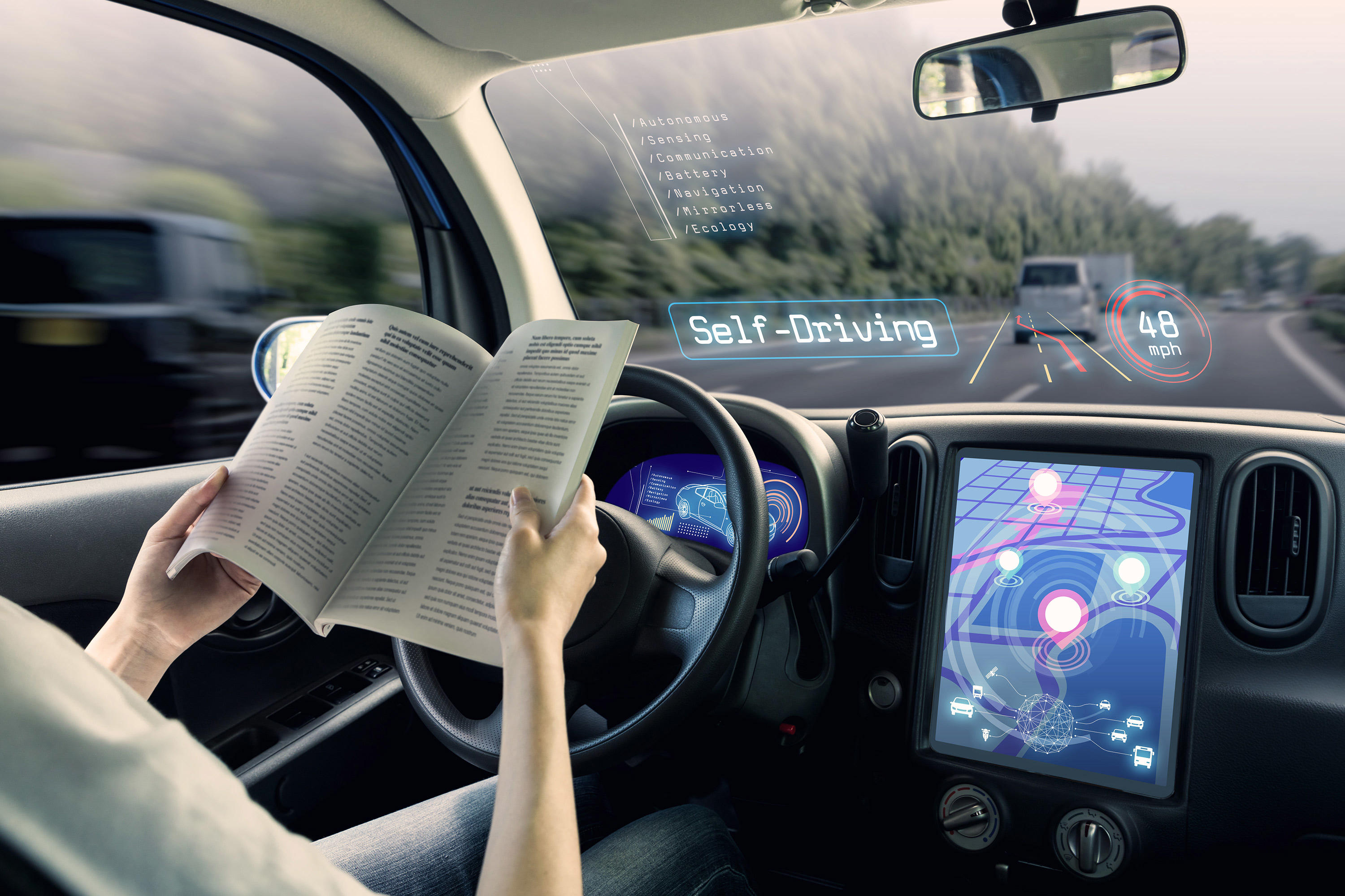 Interior of self-driving car with person reading while at the steering wheel